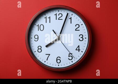 Horloge domestique rouge standard sur fond rouge Banque D'Images