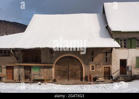 Une ancienne grange avec une grande porte voûtée et un toit recouvert de neige dans le village d'Oberdorf, en Suisse Banque D'Images