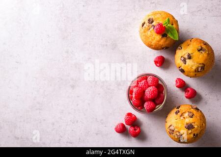 Petits gâteaux fraîchement cuits à la stracciatella garnis de feuilles de menthe à côté des framboises sur un comptoir gris Banque D'Images