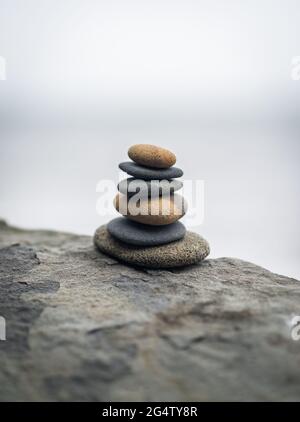 Pile de pierres zen sur le rocher dans le brouillard. Mise au point douce sélective et faible profondeur de champ. Banque D'Images