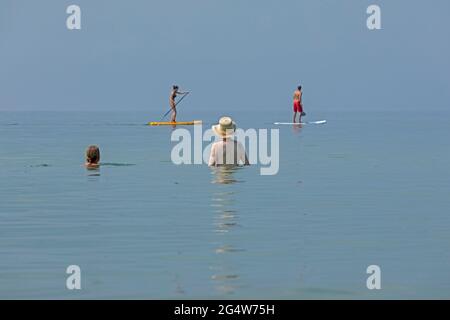 Deux femmes observant deux personnes faisant le stand-up paddle board, Wustrow, Fischland, Mecklenburg-Ouest Pomerania, Allemagne Banque D'Images