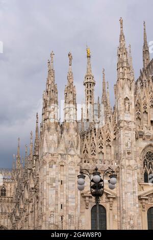 Détails du Duomo avec la statue dorée 'Madonnina' sur le dessus, ciel couvert. Banque D'Images