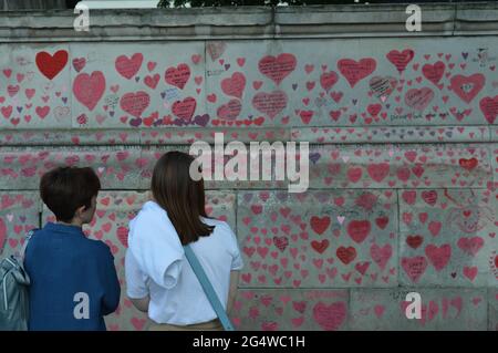 Londres, Royaume-Uni. 23 juin 2021. Deux femmes lisant les hommages écrits sur le mur commémoratif national de COVID couverts de coeurs d'amour dessinés à la main. Banque D'Images