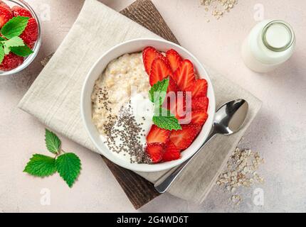 Porridge frais avec baies et graines de chia sur fond rose clair. Vue de dessus, horizontale. Banque D'Images