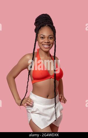 Jolie femme afro-américaine en haut orange qui a l'air joyeuse Banque D'Images