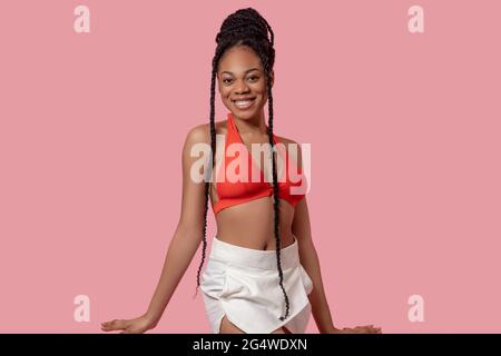 Jolie femme afro-américaine en haut orange qui a l'air joyeuse Banque D'Images