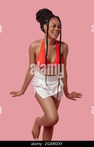 Jolie femme afro-américaine en haut orange qui a l'air joyeuse Banque D'Images