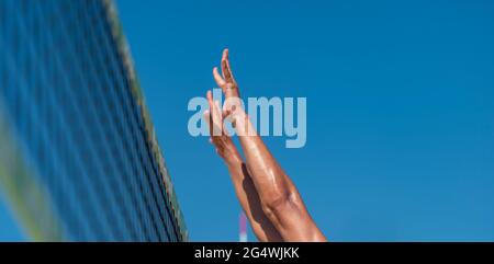 Homme d'athlétisme sautant pour faire un bloc mural au filet de Beach-volley Banque D'Images