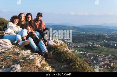 Heureux amis hommes et femmes assis sur la falaise Banque D'Images