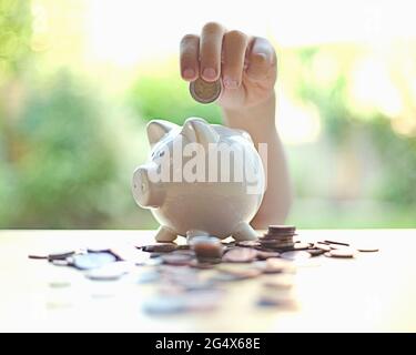 Garçon insérant la pièce dans la tirelire sur la table Banque D'Images