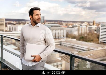 Homme d'affaires avec ordinateur portable sur le balcon du bureau Banque D'Images
