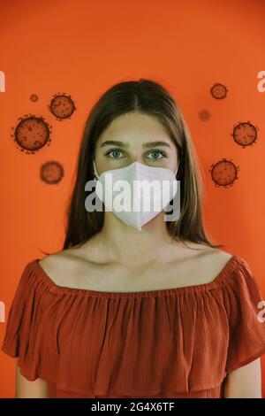 Adolescente portant un masque protecteur au milieu du virus sur fond rouge Banque D'Images