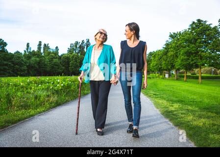 Grand-mère souriante tenant la main de la petite-fille tout en marchant sur la route Banque D'Images