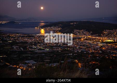 Reflet de la pleine lune dans l'eau par ville la nuit, Trogir, Croatie Banque D'Images