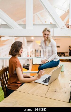 Des collègues de sexe féminin discutent sur ordinateur portable tout en travaillant ensemble dans un bureau créatif Banque D'Images