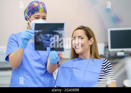 Dentiste de sexe féminin présentant une radiographie au patient à la clinique Banque D'Images