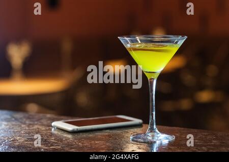 Buvez dans un verre de martini par téléphone portable sur la table Banque D'Images