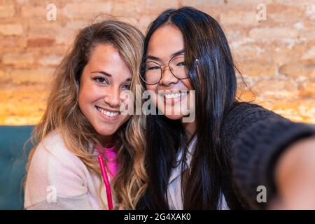 Des amies souriantes emportant un selfie au bar Banque D'Images