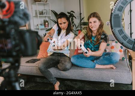Concentration de gamers féminins jouant à des jeux vidéo tout en vlogging à la maison Banque D'Images