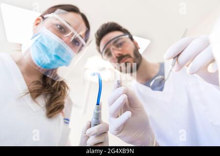 Femme dentiste avec un collègue tenant l'équipement dentaire à la clinique Banque D'Images