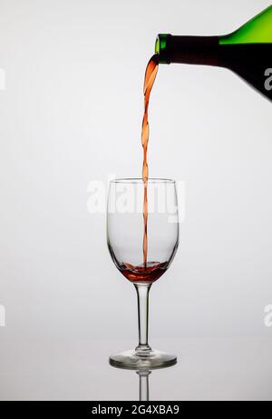 Verser le vin rouge dans un verre transparent. Banque D'Images