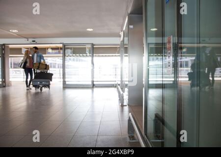 Jeune couple avec chariot à bagages au terminal de l'aéroport Banque D'Images