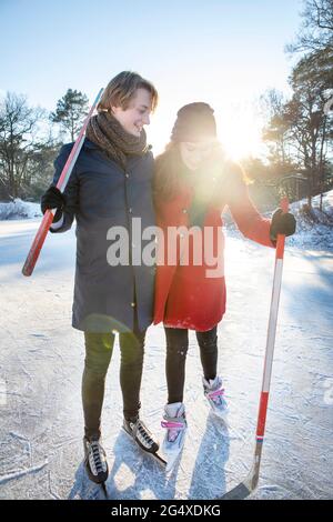 Couple tenant des bâtons de hockey sur glace en jouant sur le lac gelé Banque D'Images