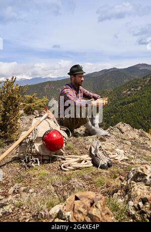 Adulte de taille moyenne, homme, tenant une tasse tout en étant assis sur la montagne Banque D'Images