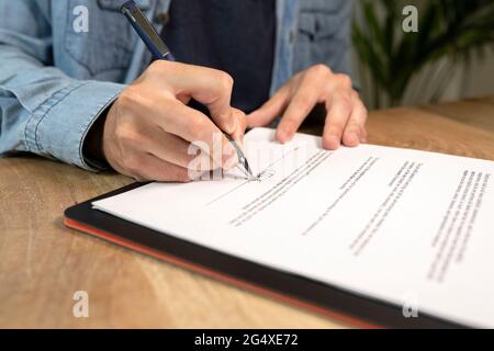 Homme d'affaires faisant la signature sur contrat à la réception dans le bureau Banque D'Images