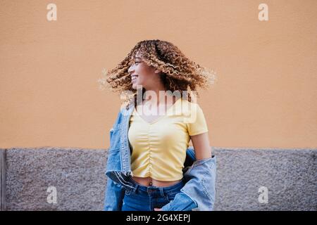 Belle femme avec cheveux touffés par le mur Banque D'Images