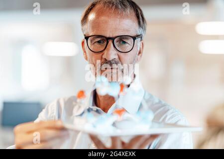 Brainstorming d'entrepreneur masculin sur la structure des molécules au bureau Banque D'Images