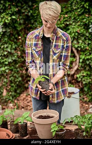 Femme mettant la plante dans le pot de fleur à l'arrière-cour Banque D'Images