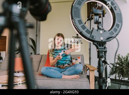 Gamer féminin jouant au jeu tout en vlogging à la maison Banque D'Images