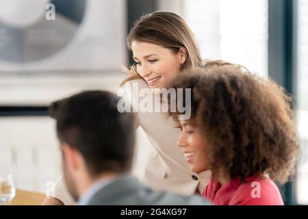 Souriants professionnels hommes et femmes discutant au bureau Banque D'Images