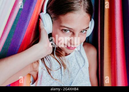 Fille souriante appréciant la musique d'écoute dans le hamac Banque D'Images