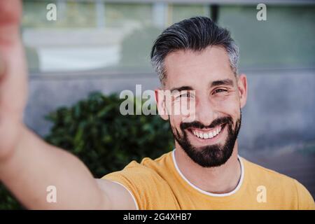 Homme souriant prenant le selfie par le biais d'un smartphone Banque D'Images