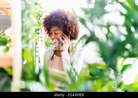 Une fleuriste féminine parle au téléphone portable dans un magasin de l'usine Banque D'Images