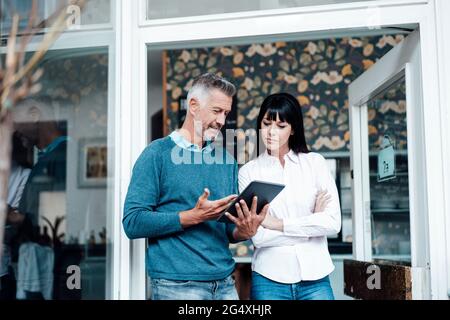 Homme d'affaires avec tablette numérique expliquant à un collègue au café Banque D'Images