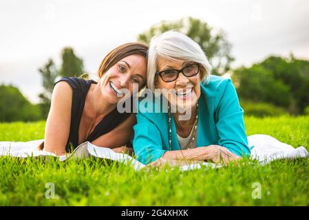 Petite-fille souriante couchée par la grand-mère sur la prairie Banque D'Images