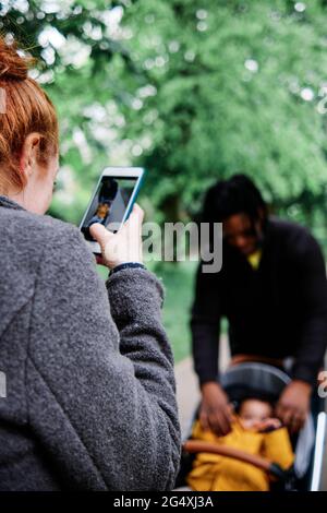 Mère photographiant son fils dans une poussette au parc Banque D'Images