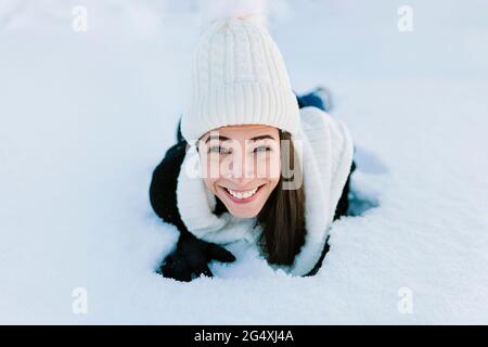 Bonne femme en tricot, couchée sur la neige Banque D'Images