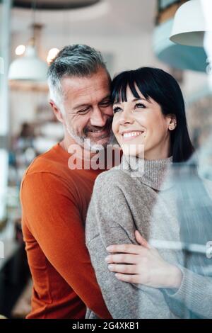 Couple mûr souriant debout ensemble au café Banque D'Images