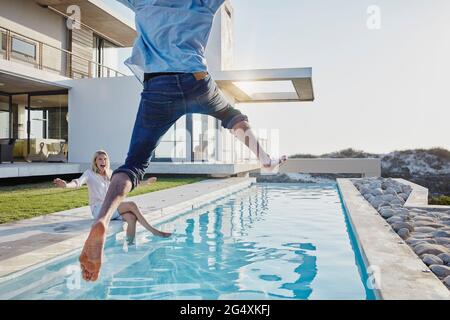 Bonne femme regardant l'homme sauter dans la piscine Banque D'Images