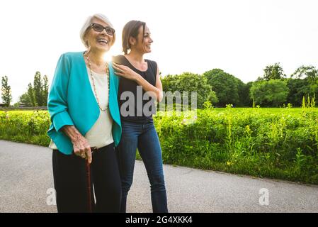 Une femme âgée heureuse marchant avec une femme adulte de taille moyenne dans le parc Banque D'Images