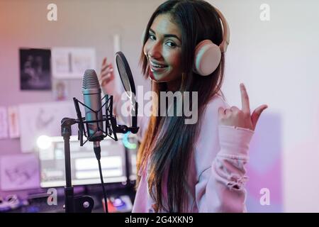 Une chanteuse souriante qui porte un casque gestuelle en chantant en studio Banque D'Images