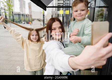 Mère souriante prenant le selfie avec des enfants en ville Banque D'Images