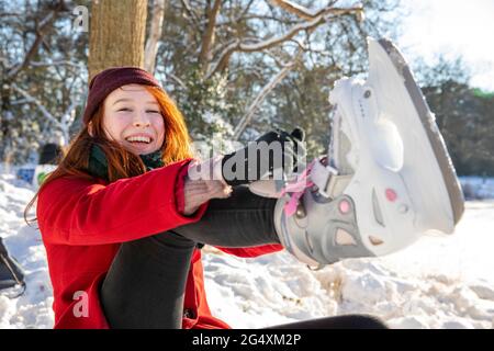 Femme souriante portant un patin à glace pendant l'hiver Banque D'Images