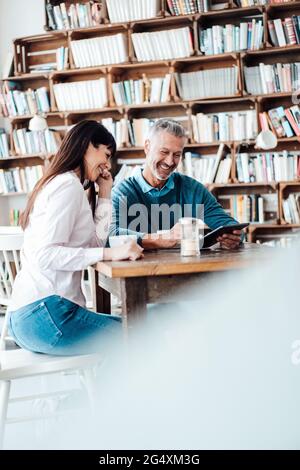 Les propriétaires de sexe masculin et féminin utilisent une tablette numérique dans un café Banque D'Images