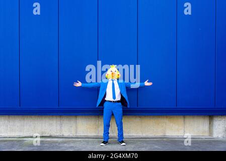 Homme portant un costume bleu vif et un masque d'oiseau debout à l'extérieur avec les bras ouverts Banque D'Images