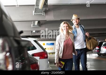 Un jeune couple se promenant dans le parking de l'aéroport Banque D'Images